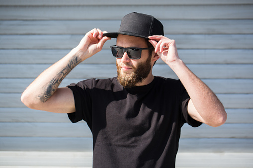 Hipster handsome male model with beard  wearing black blank baseball cap with space for your logo