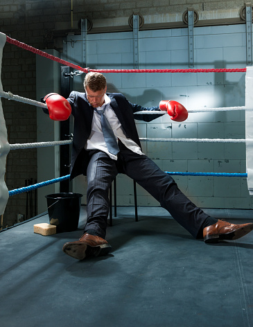 Man, white collar worker in the corner of a box ring knocked out, low angle view