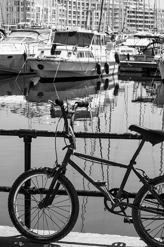 Flaked bicycle on the embankment of Valletta. Yachts docked at the port of Malta. Black and white picture