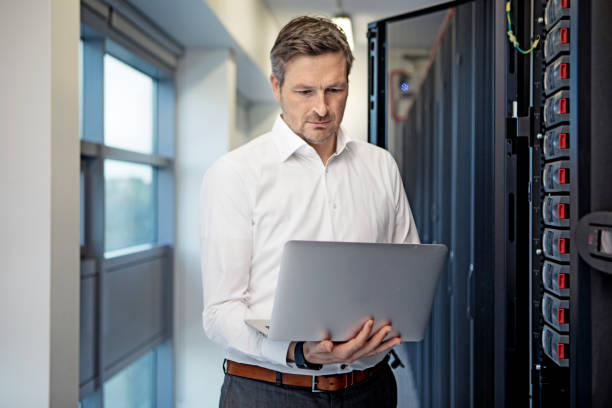 Adult Male Technician Manager working in Server Room Setting Adult Male Technician Manager working in Server Room Setting data center photos stock pictures, royalty-free photos & images