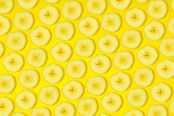 Slices of fresh bananas on yellow background.