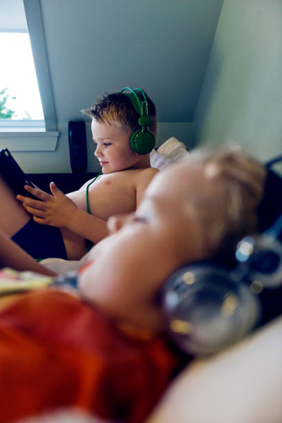 istock Two kids are lying in bed watching content on their digital tablets before going to sleep 858180898