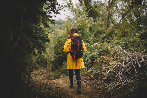 Young woman in the yellow raincoat walking in forest