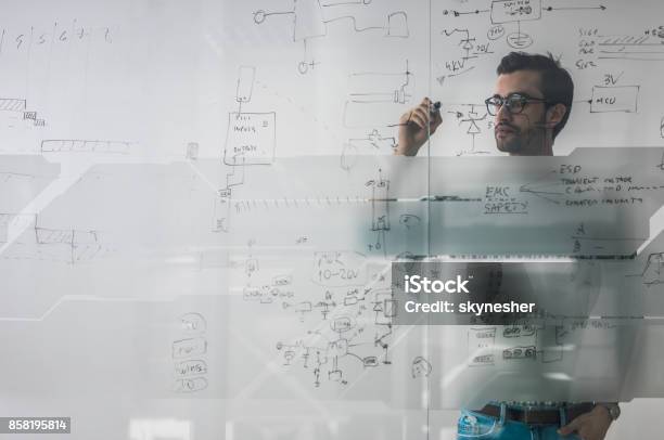 Männliche Ingenieur Arbeitet An Neuen Ideen Und Schreibt Diagramm An Glaswand Stockfoto und mehr Bilder von Komplexität