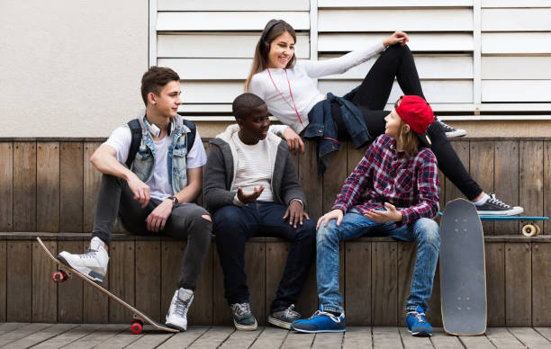 istock girl and three boys hanging out outdoors and discussing something 858215770