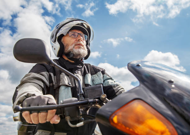 elderly motorcyclist wearing a jacket and glasses with a helmet
