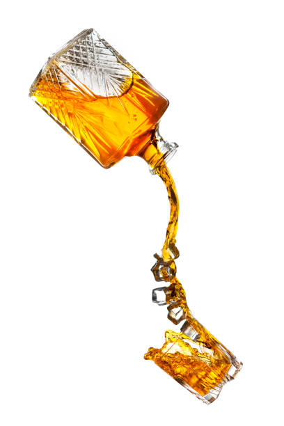 Pouring Liquor Bottle pouring splash of liquor and ice in a glass pouring stock pictures, royalty-free photos & images