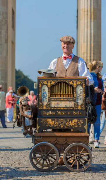 Man playing the barrel organ for the tourists in front of the Brandenburg Gate in Berlin Germany Berlin, Germany - September 17, 2014 : Man playing the hand organ for the tourists in front of the Brandenburg Gate in Berlin Germany hurdy gurdy stock pictures, royalty-free photos & images