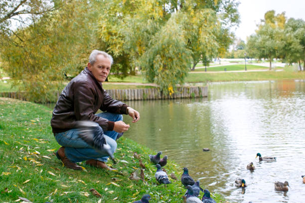 istock lonely elderly man feeding ducks in a deserted park 858235340