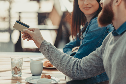 cropped shot of young beautiful couple paying with credit card in cafe