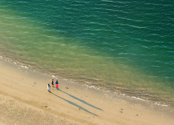 Photographer's shadow on the sand. Man doing the photo of his shadow on the sand. Shadow of a man on sandy beach. Silhouette close to sea water.