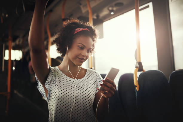 バスで音楽を聴く若いアフリカ女性の笑みを浮かべてください。 - metro bus ストックフォトと画像