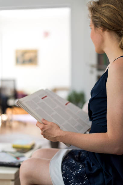 istock Woman sitting at home on a couch and is reading a magazine article 858256716