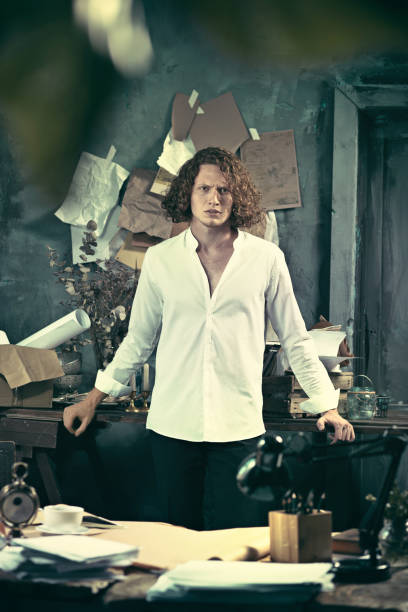 istock Writer at work. Handsome young writer standing near the table and making up something in his mind 858257600