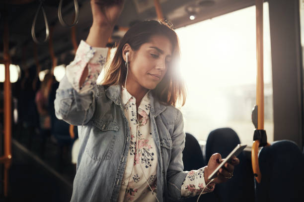 音楽を聞いてバスに立っている若い女性 - metro bus ストックフォトと画像