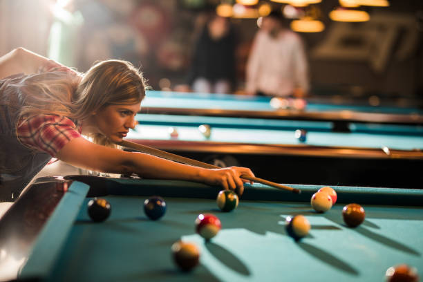istock Young woman aiming at the pool ball while playing snooker in a pub. 858272514