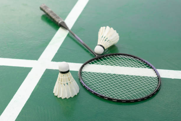 Badminton racket and shuttlecocks on court.. Badminton racket and shuttlecocks on green court.. badminton racket stock pictures, royalty-free photos & images