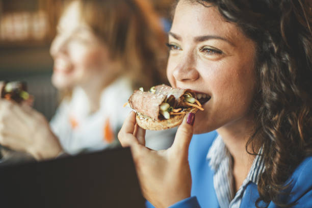 Young women on a lunch break Young women are having a break at cafe. They are enjoying their healthy meal. cafeteria sandwich food healthy eating stock pictures, royalty-free photos & images