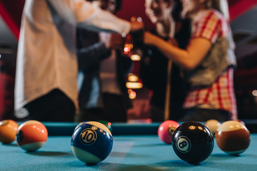 Close up of billiard balls on the table with people in the background.