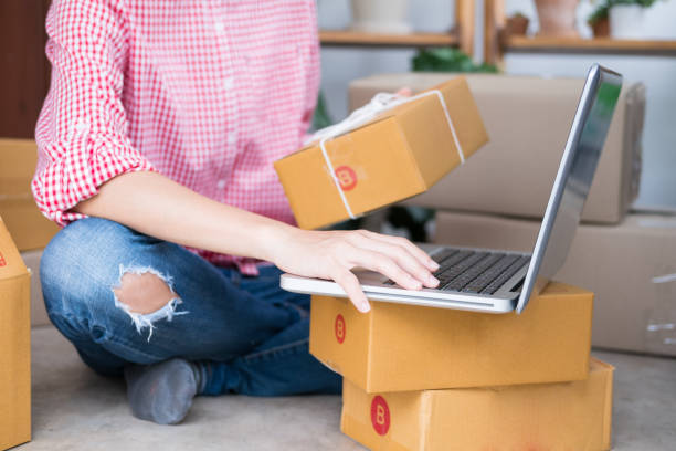 istock start up small business owner checking product order with computer at workplace. freelance woman entrepreneur SME seller prepare parcel box for deliver to customer.  Online selling, internet marketing, e-commerce, shipping concept 858289770