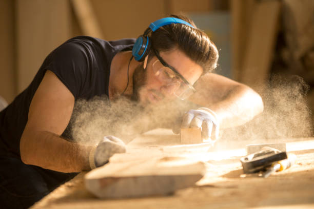 istock Young handosme carpenter blowing off sawdust 858292482