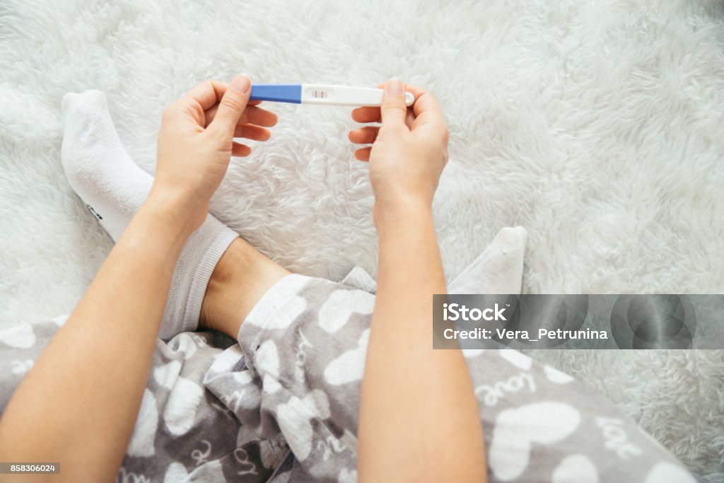 sad woman with pregnancy test sad woman looking on pregnancy test unexpected Pregnant Stock Photo