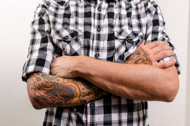 Closeup man with crossed tattooed arms , fashion macho man concept
