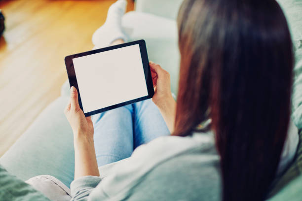 femme aux cheveux bruns, tenant une tablette numérique à la maison - women computer home interior brown hair photos et images de collection