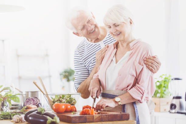 istock Elder woman is cutting tomatoes 858315694
