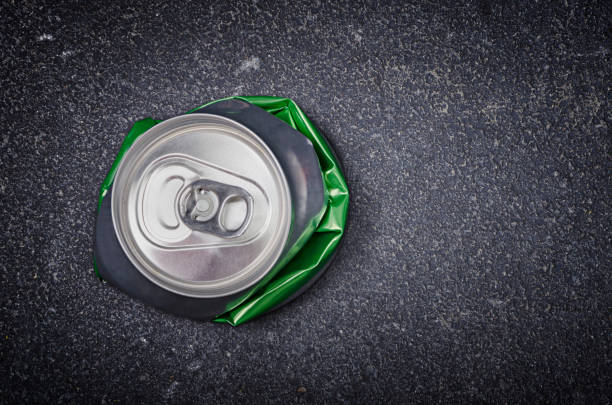 Crushed aluminum beer can on asphalt street background