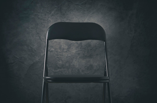 Empty interview chair against a dark background.