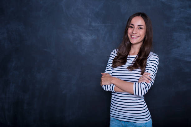 istock Pretty happy young woman standing over chalkboard background 858326634