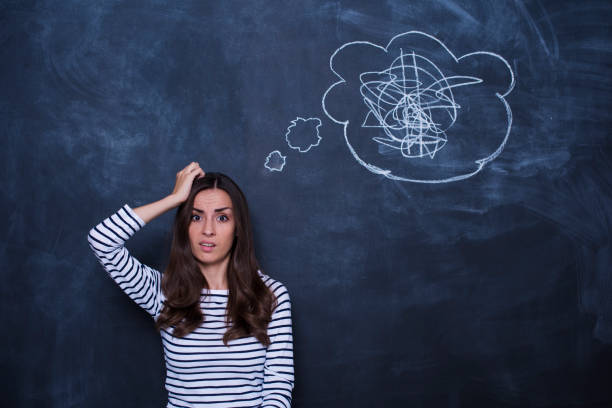 istock Frowning thougthful young woman thinking about problems over blackboard background 858327056