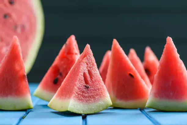 Many bright juicy watermelon slices cut into triangular shape. Summer refreshing snack closeup