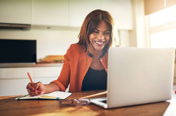 istock Smiling young female entrepreneur working online at her kitchen table 858337752