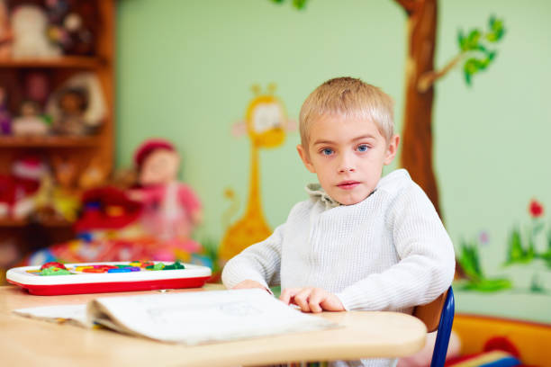 istock cute boy, kid with special needs learning in rehabilitation center 858340712