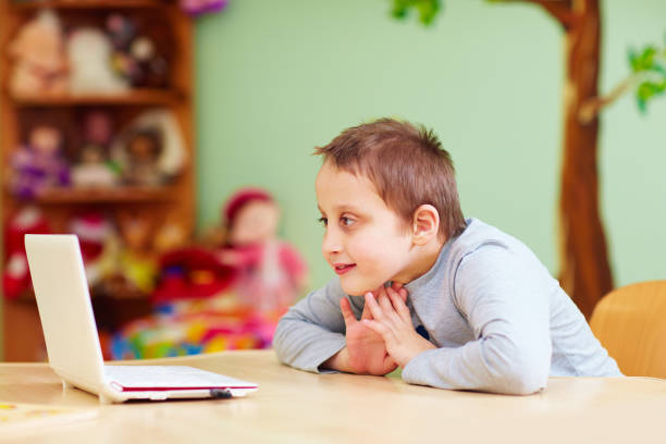 istock young boy with special needs watching media through the laptop 858341060