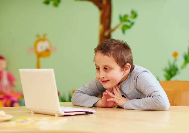young boy with special needs watching media through the laptop
