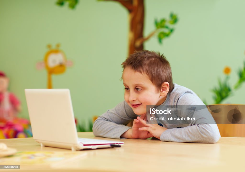 young boy with special needs watching media through the laptop Child Stock Photo