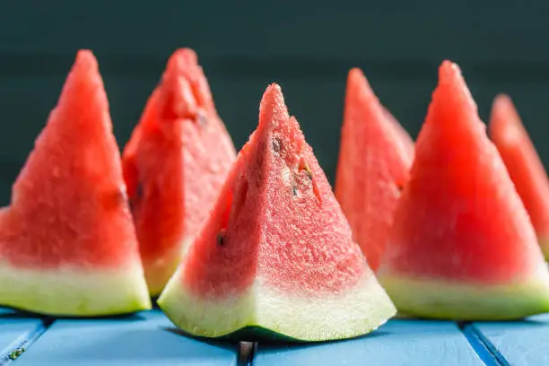 Fresh bright juicy triangular watermelon slices on blue background. Healthy vegan snack in summer closeup