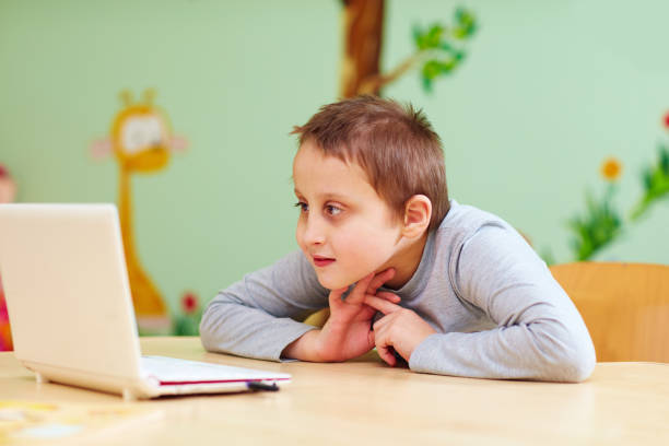 istock young boy with special needs watching video through the laptop 858344050