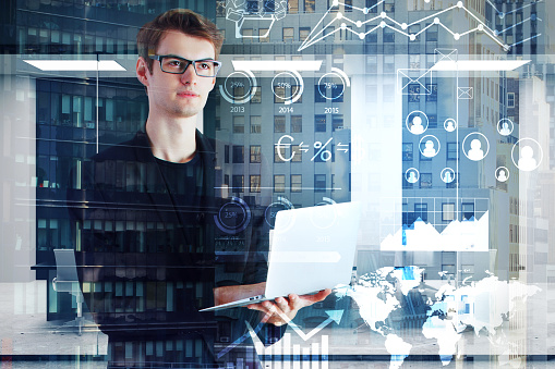 Handsome young european businessman using laptop on abstract city background. Communication and finance concept. Double exposure