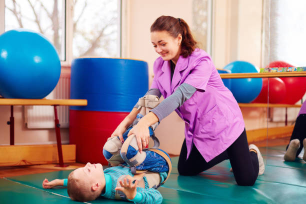 istock cute kid with disability has musculoskeletal therapy by doing exercises in body fixing belts 858345384