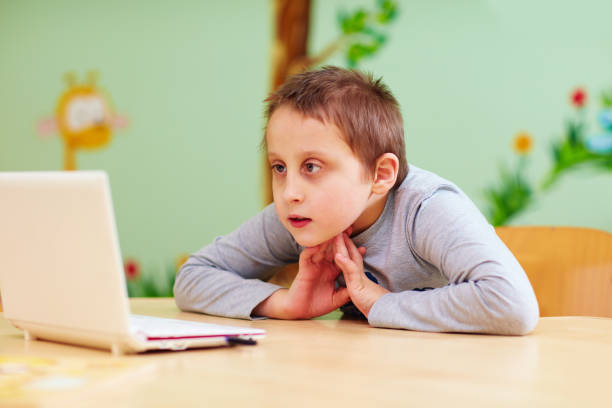 istock young boy with special needs watching video through the laptop 858345542