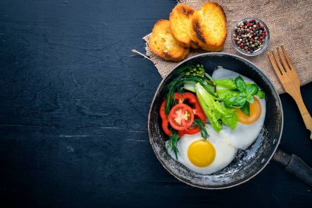 istock Fried egg with herbs, toast bread and vegetables in a frying pan. Top view. Free space. 858345824