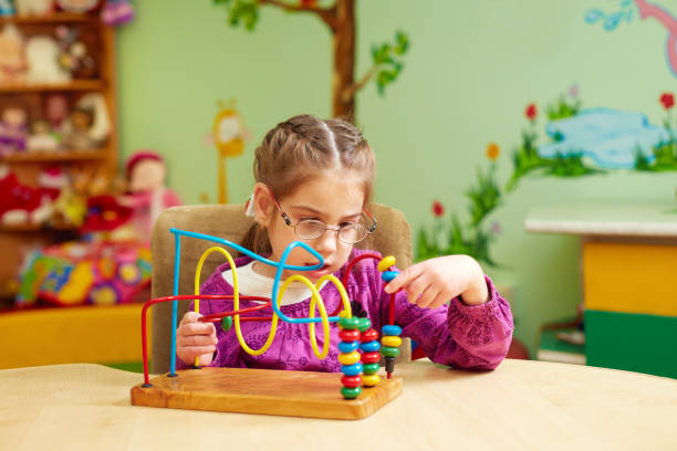 istock cute little girl playing with developing toy in kindergarten for kids with special needs 858348134