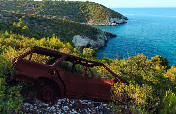 Broken demage rusty car on summer sea coast hill near Arch of San Felice on the Gargano peninsula in Puglia, Italy