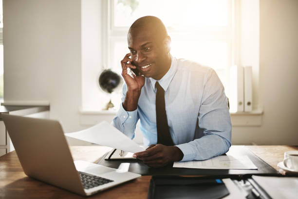 istock Young businessman sitting at work discussing paperwork over the phone 858349406