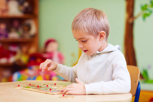 istock cute boy, kid with special needs solving a puzzle in rehabilitation center 858355360