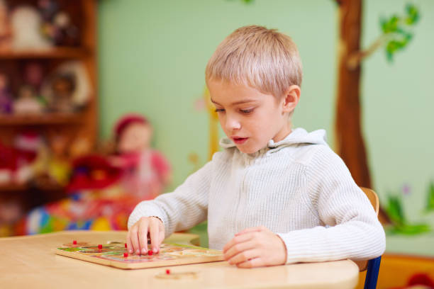 istock cute boy, kid with special needs solving a puzzle in rehabilitation center 858358158